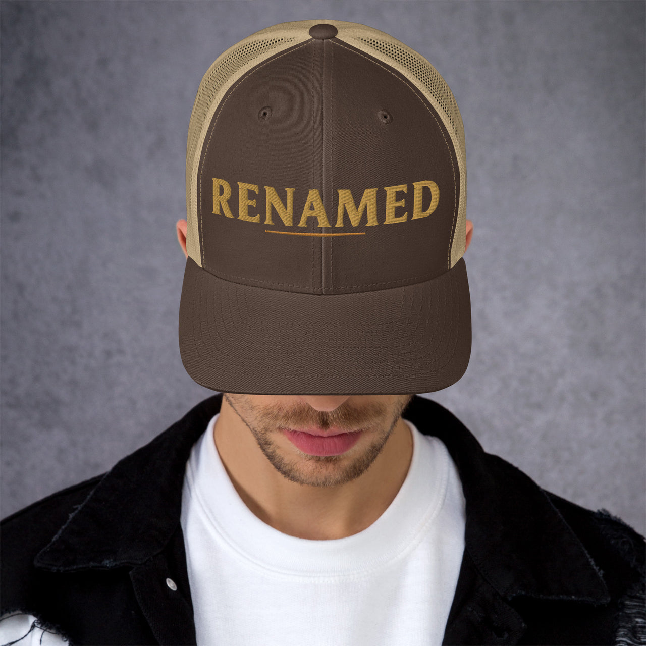 Male model wearing Renamed Trucker Cap in Brown/Khaki, angled front view showing embroidered design