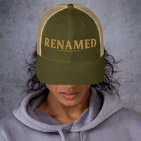 Female model wearing Renamed Trucker Cap in Moss/Khaki, angled front view showing embroidered design