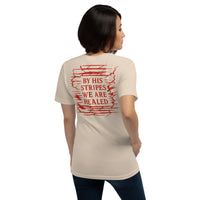 Female model wearing soft cream gospel tee – back print reads “By His stripes we are healed”