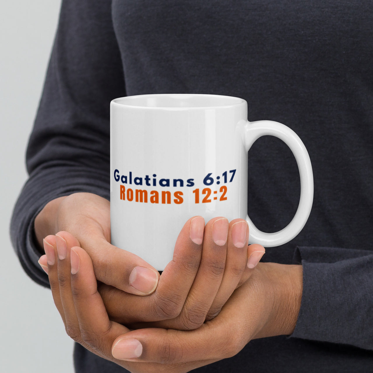 Model holding 11oz Christian mug – scripture side featuring Romans 12:2 and Galatians 6:17