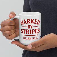 Model holding 15oz Marked by Stripes glossy ceramic mug – red embroidered logo side visible